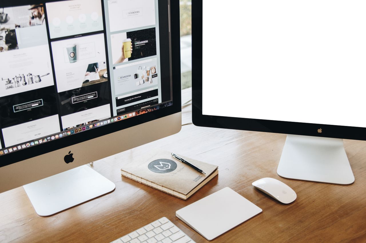 Vue plongeante sur un bureau élégant équipé de deux écrans, clavier, souris, et accessoires contemporains.